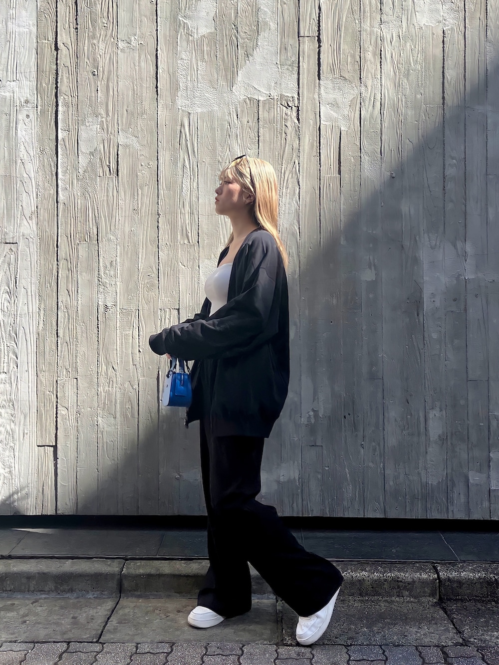 ホワイト系のキャミソール、ブラック系のカーディガン/ボレロ、ブルー系のハンドバッグを着用したレディースの春コーディネートの3枚目の写真