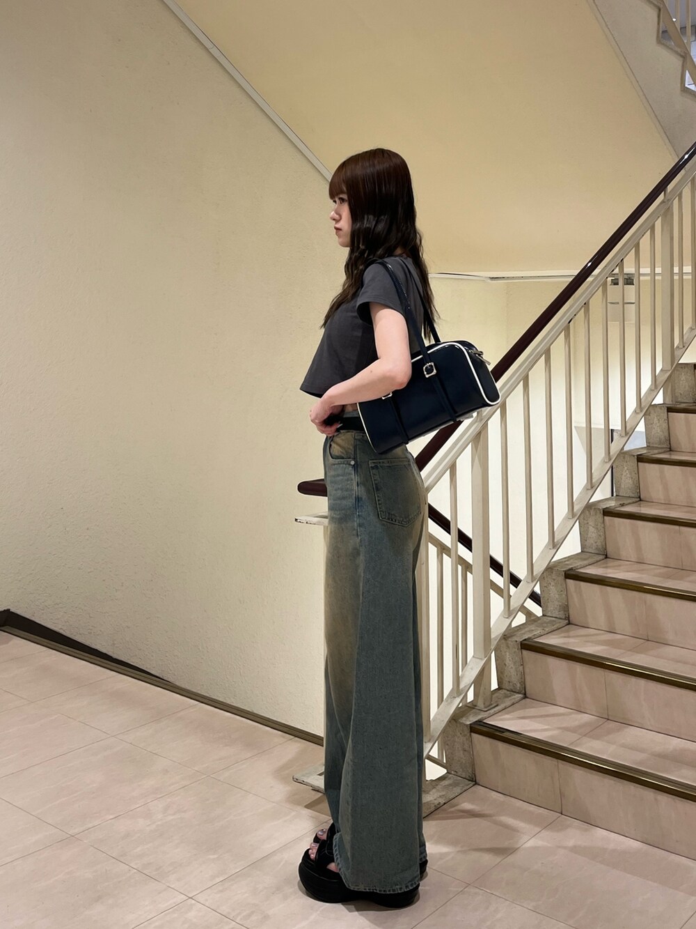 ブルー系のデニムパンツ、ブラック系のサンダル、グレー系のTシャツ/カットソーを着用したレディースの春コーディネートの2枚目の写真