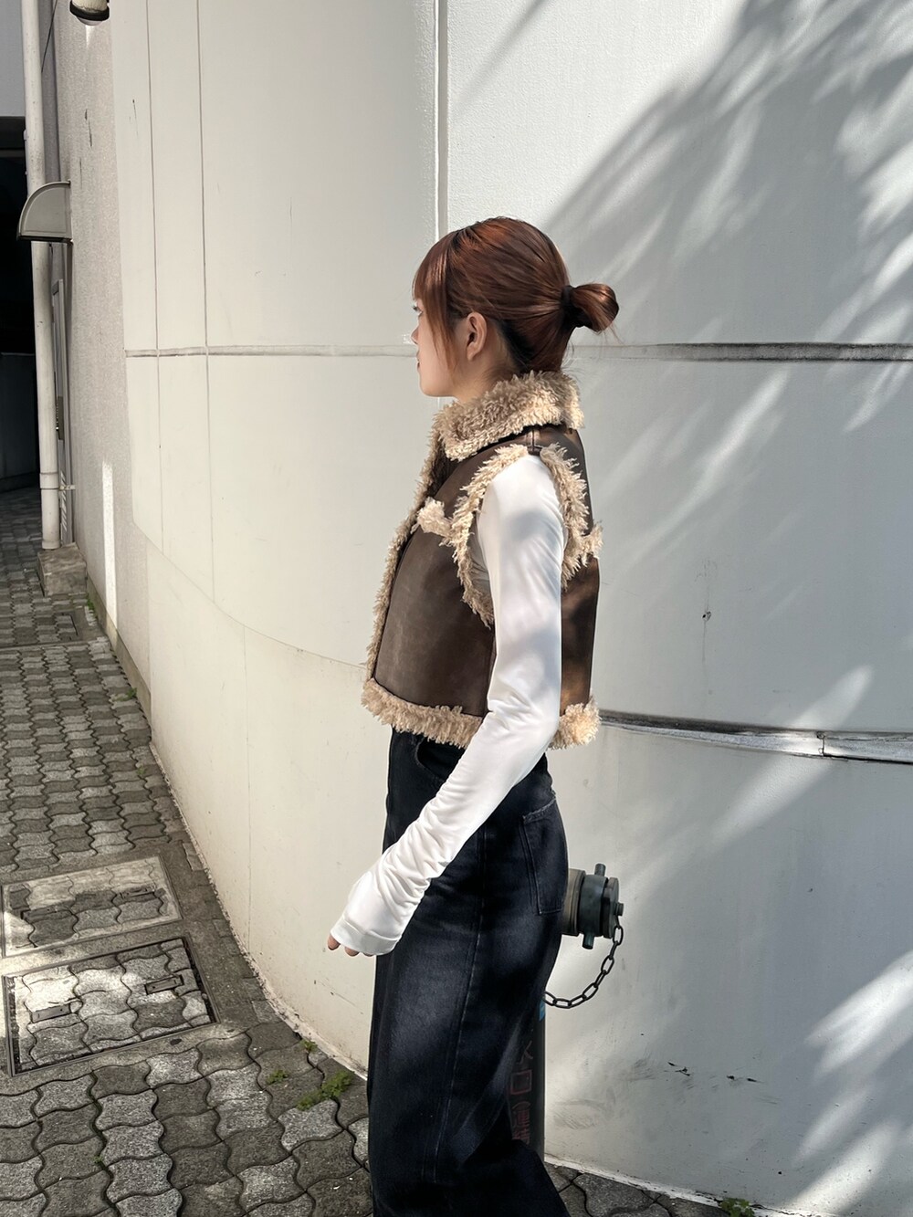 ブラック系のデニムパンツ、ブラック系のブーツ、ブラウン系のベストを着用したレディースの秋コーディネートの7枚目の写真