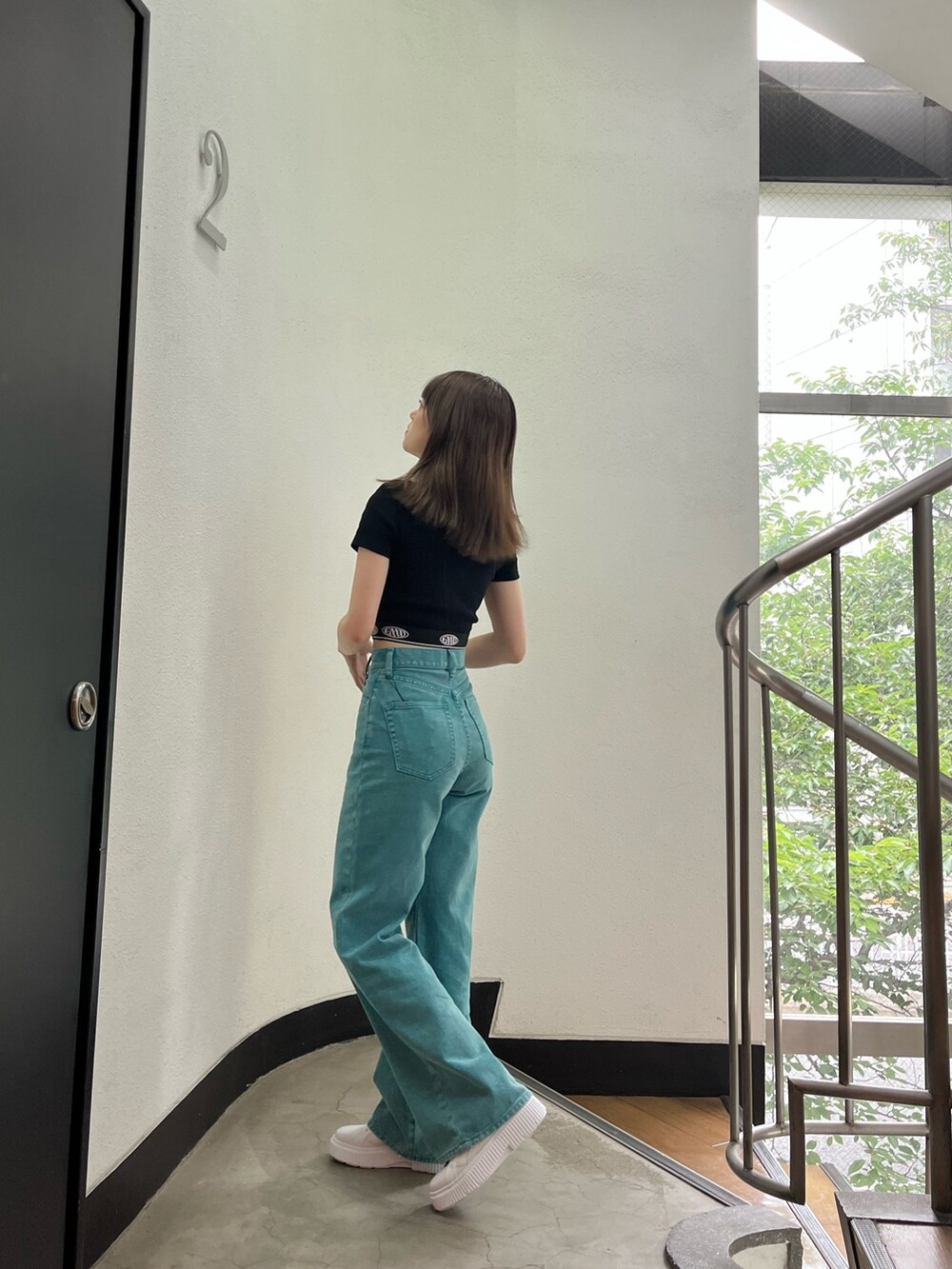 グリーン系のデニムパンツ、ブラック系のTシャツ/カットソー、ホワイト系のスニーカーを着用したレディースの夏コーディネートの2枚目の写真