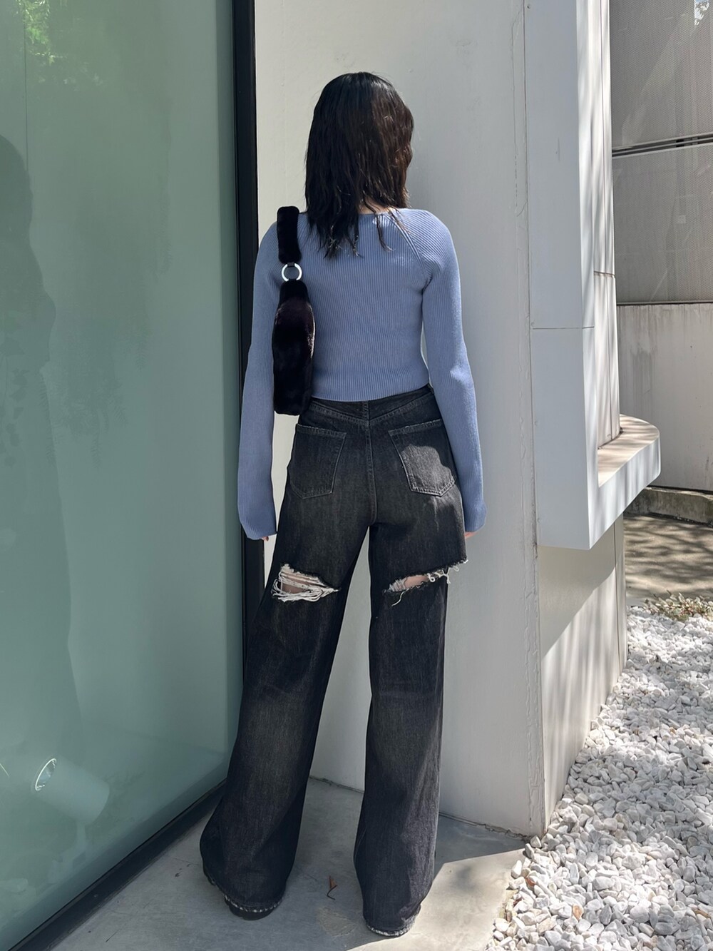 ブラック系のデニムパンツ、ブラック系のブーツ、ブルー系のニット/セーターを着用したレディースの秋コーディネートの3枚目の写真