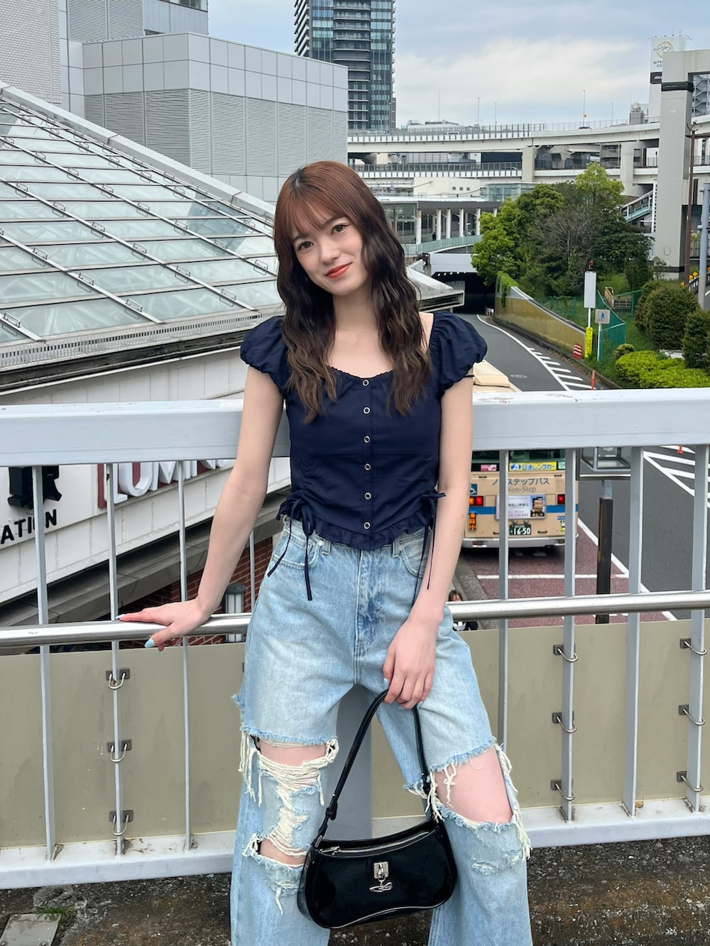 ブラック系のパンプス、ブラック系のショルダーバッグ、ブルー系のデニムパンツを着用したレディースの春コーディネートの4枚目の写真