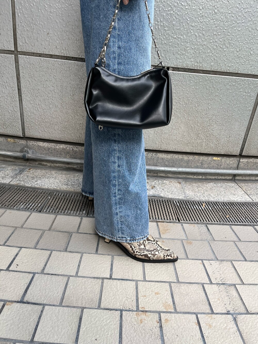 ブルー系のデニムパンツ、ブラック系のニット/セーター、ブラック系のハンドバッグを着用したレディースの秋コーディネートの6枚目の写真