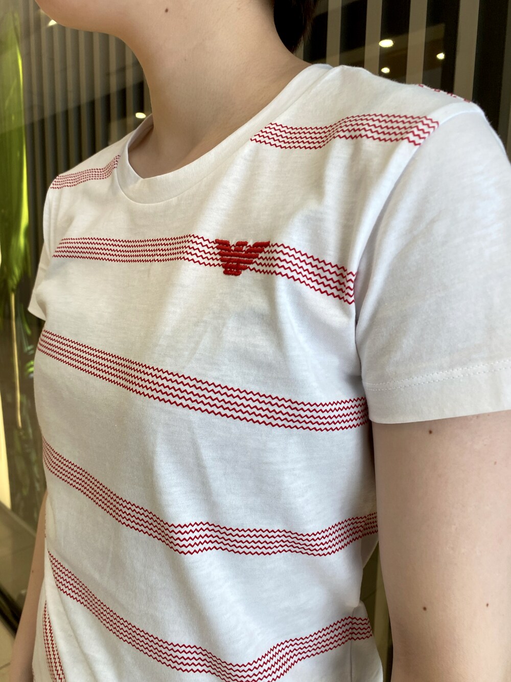 ブラック系のバッグ、ブルー系のデニムパンツ、ホワイト系のスニーカーを着用したレディースの夏コーディネートの2枚目の写真