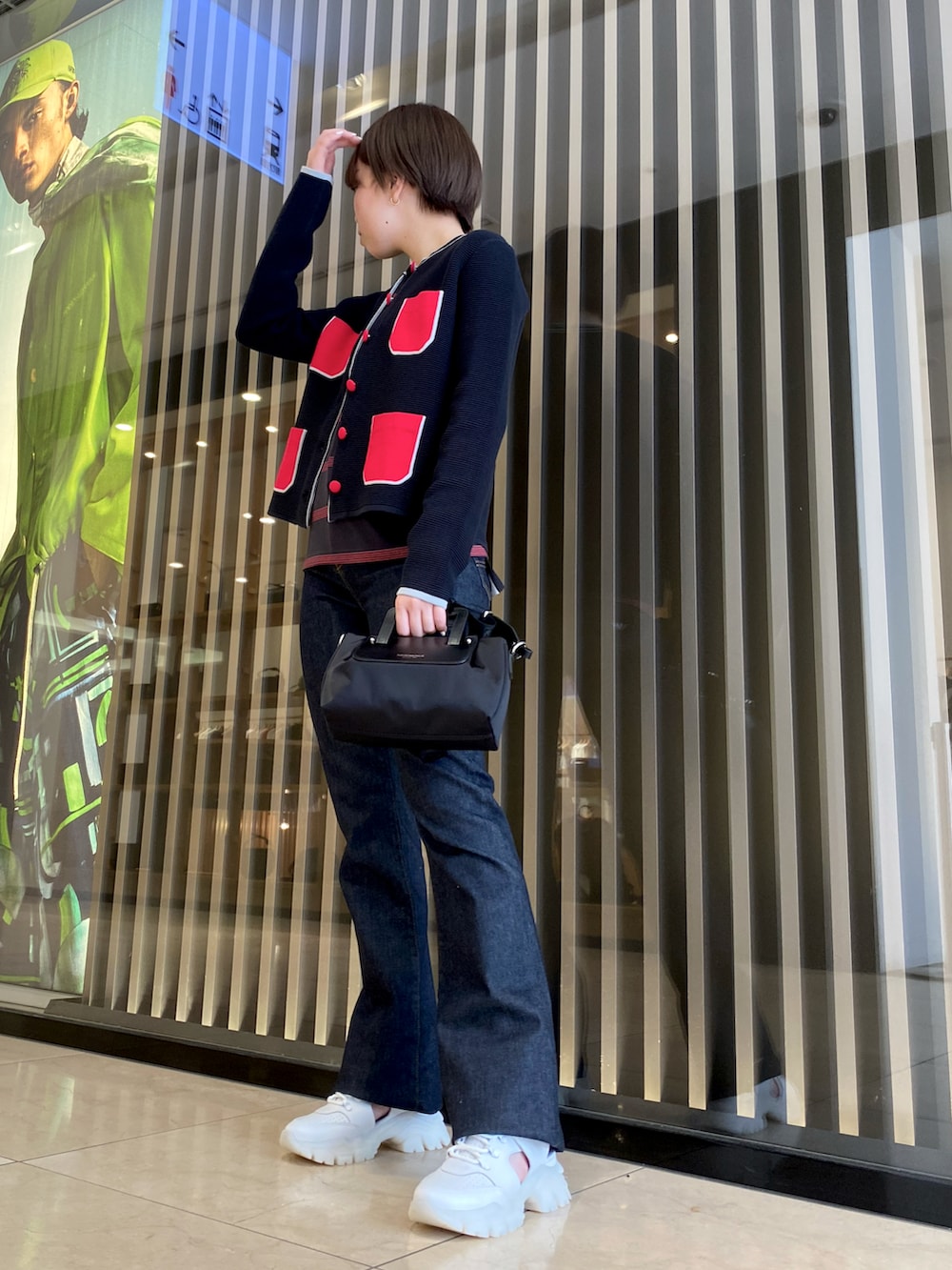 ブラック系のバッグ、ブルー系のデニムパンツ、ホワイト系のスニーカーを着用したレディースの夏コーディネートの5枚目の写真