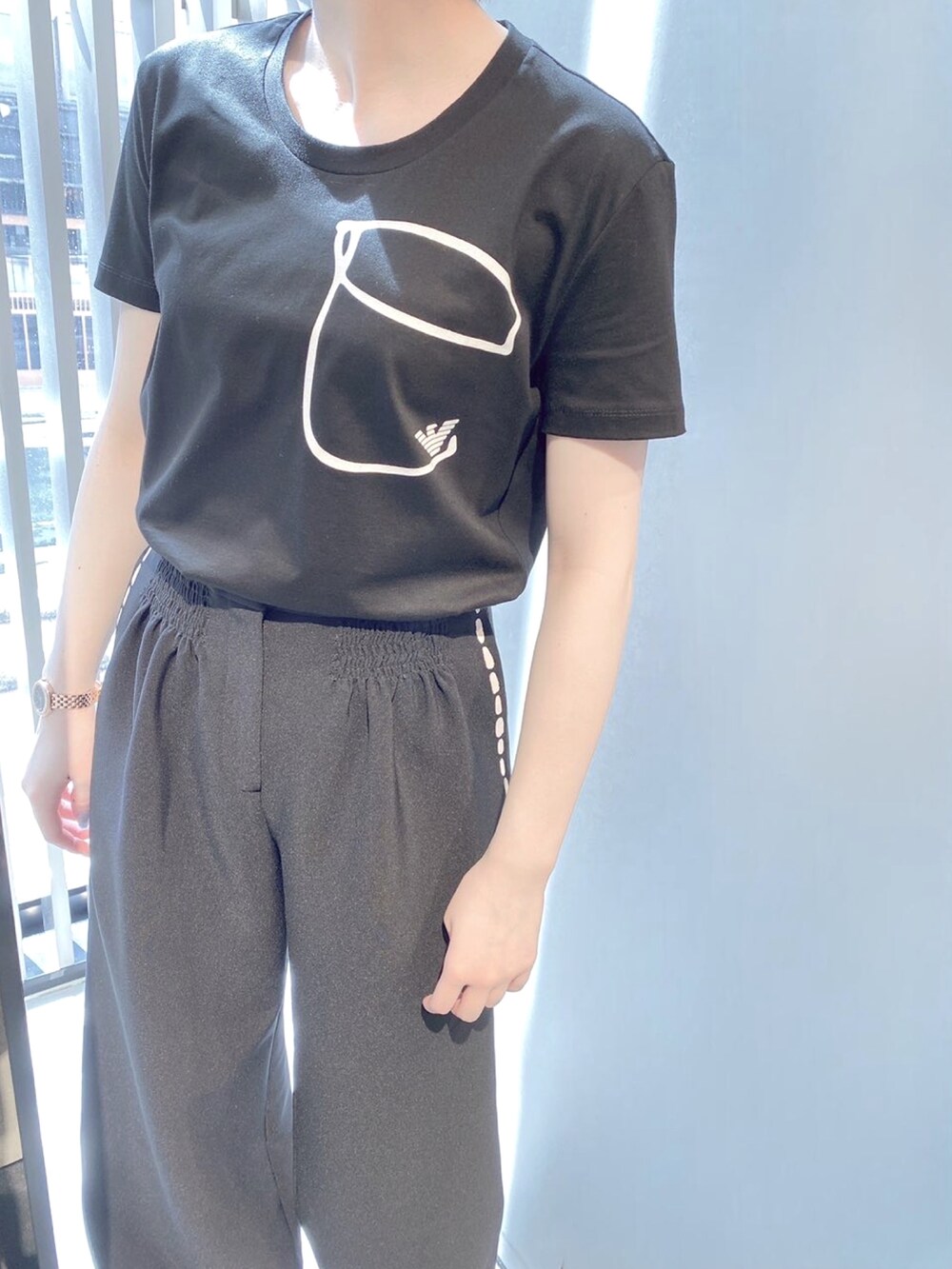 ホワイト系のTシャツ/カットソー、ブラック系のパンツ、ホワイト系のスニーカーを着用したレディースの夏コーディネートの4枚目の写真