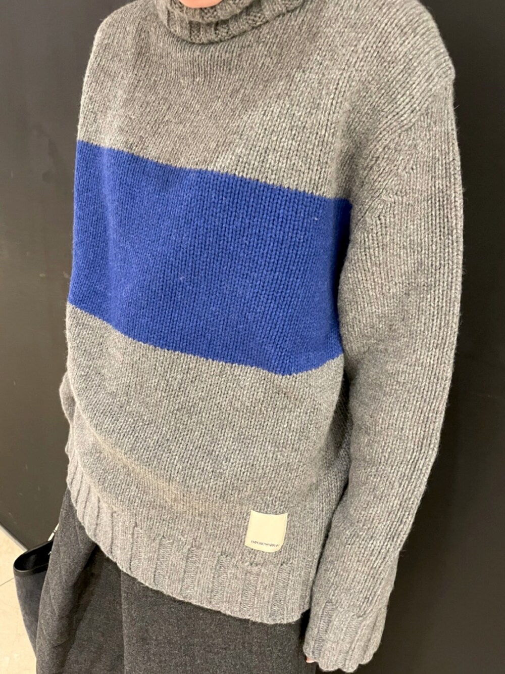 グレー系のニット/セーター、グレー系のスカート、グレー系のショルダーバッグを着用したレディースの秋コーディネートの2枚目の写真