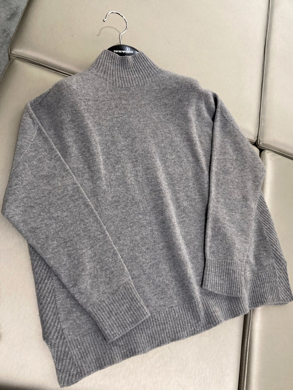 グレー系のニット/セーター、パープル系のチェスターコート、ホワイト系のハンドバッグを着用したレディースの秋コーディネートの2枚目の写真