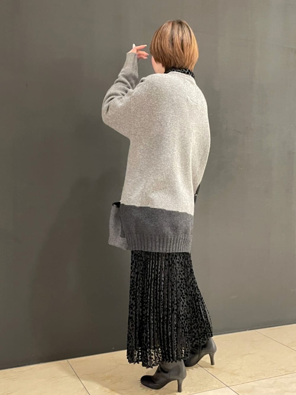 グレー系のニット/セーター、ブラック系のドレス、グレー系のショルダーバッグを着用したレディースの秋コーディネートの2枚目の写真