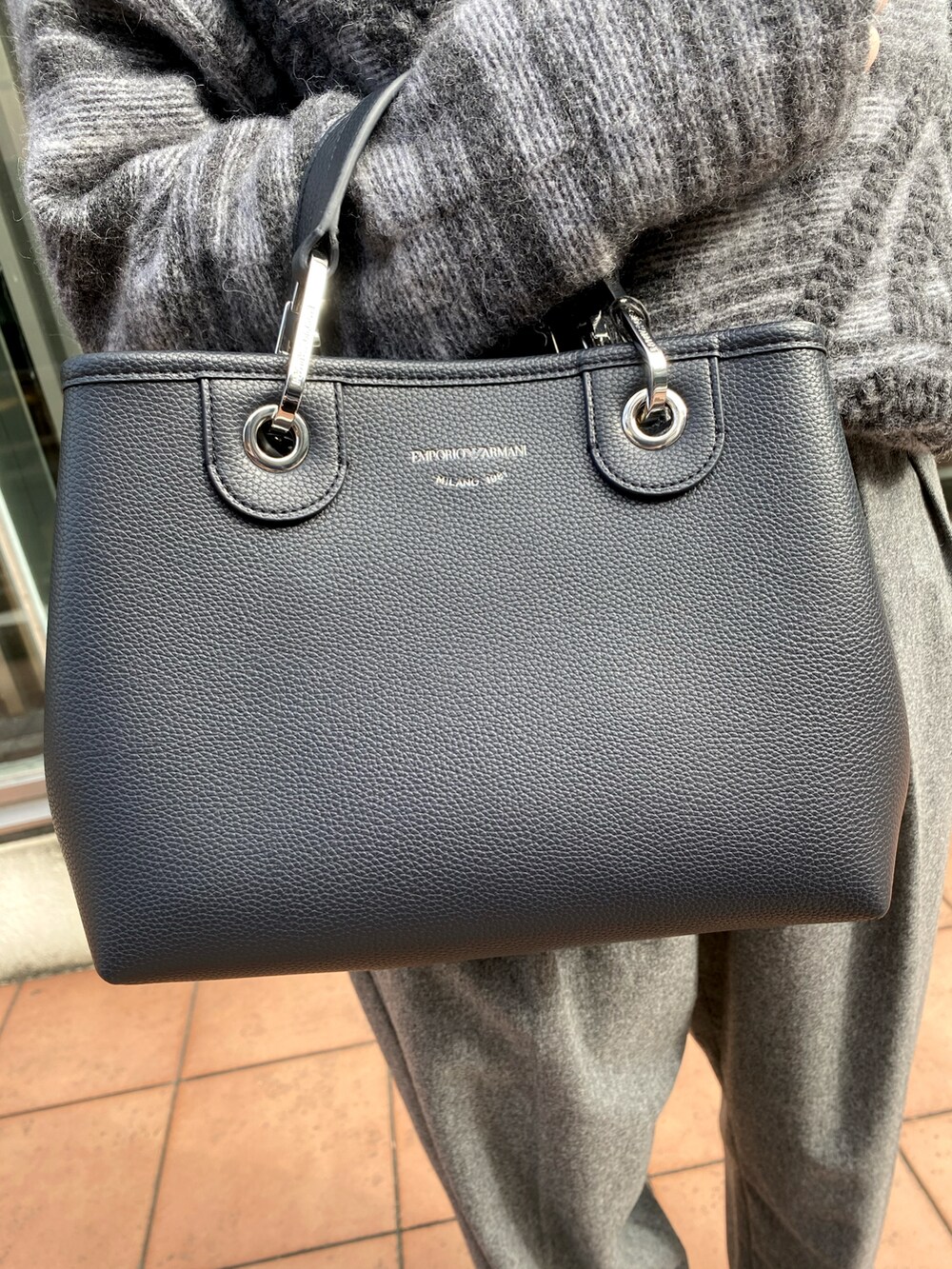 グレー系のニット/セーター、ブルー系のシャツ/ブラウス、グレー系のパンツを着用したレディースの秋コーディネートの4枚目の写真