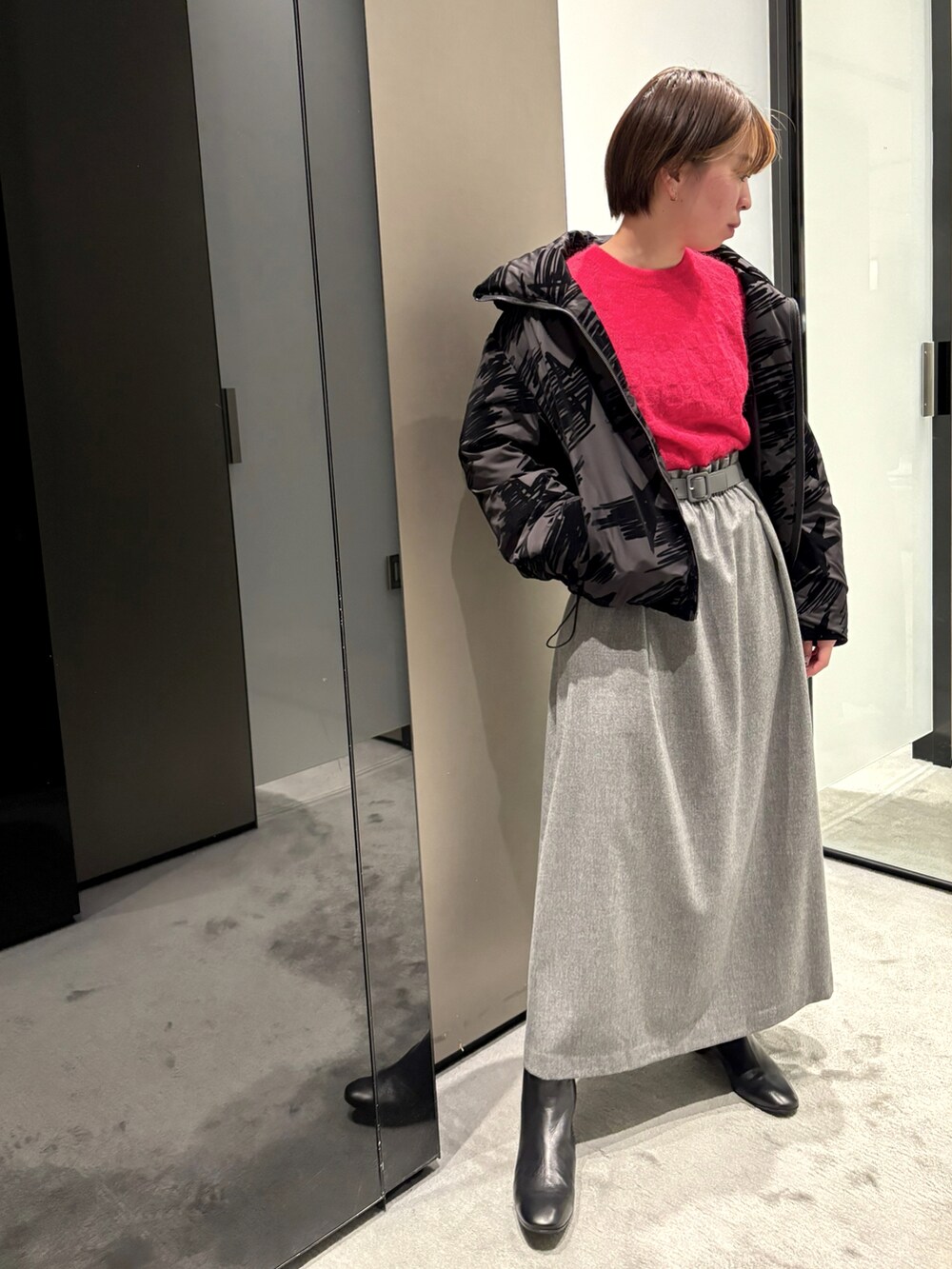 ブラック系のダウンジャケット/コート、レッド系のニット/セーター、グレー系のスカートを着用したレディースの秋コーディネートの2枚目の写真