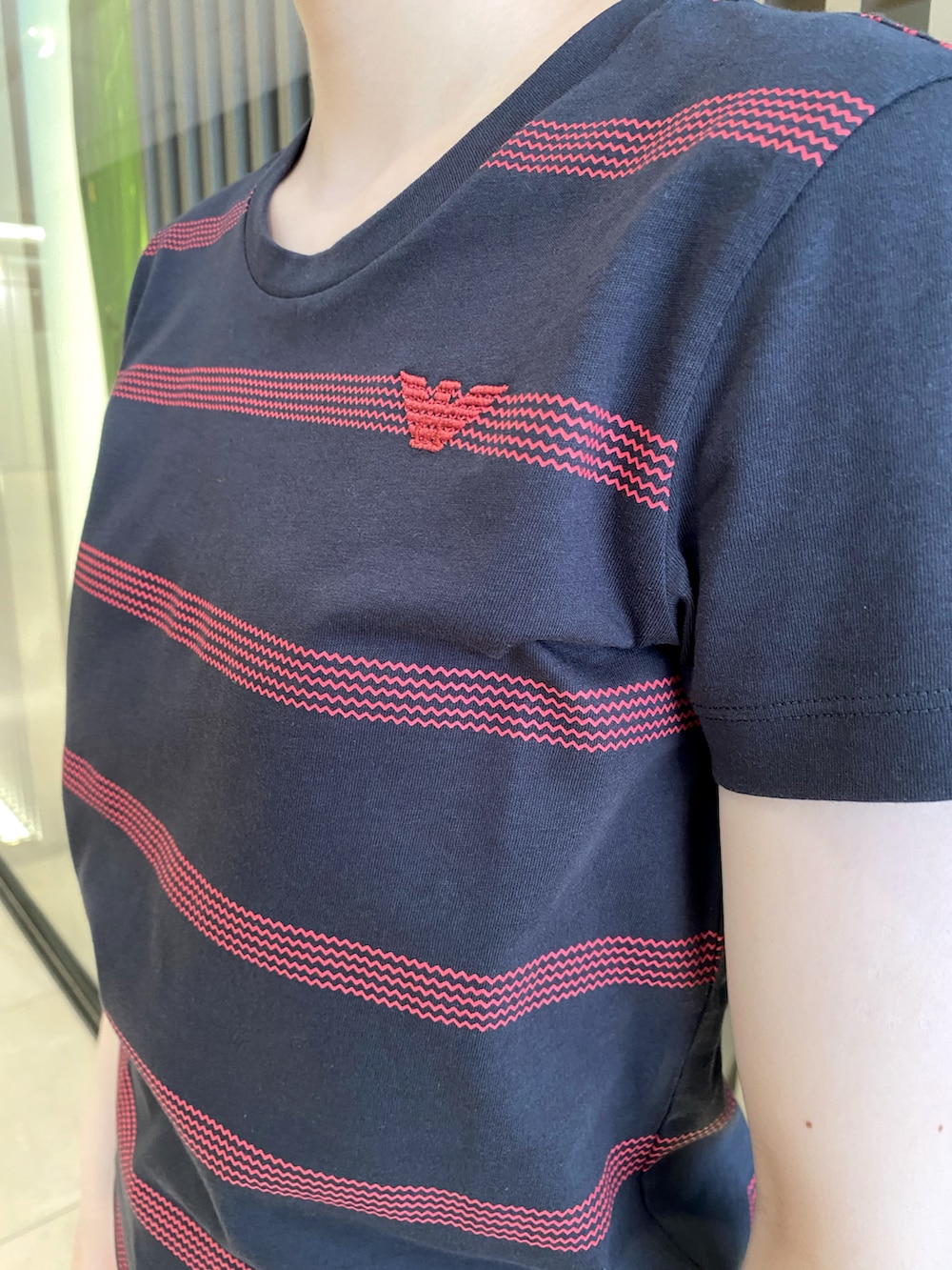 ブラック系のバッグ、ブルー系のデニムパンツ、ホワイト系のスニーカーを着用したレディースの夏コーディネートの4枚目の写真