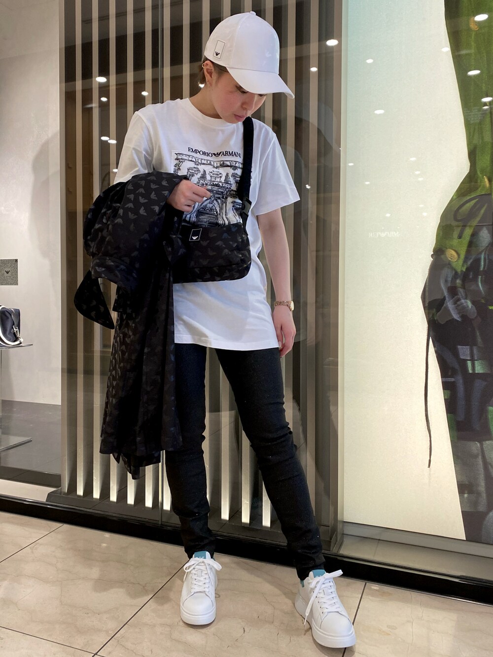 ホワイト系のTシャツ/カットソー、ブラック系のデニムパンツ、ブラック系のトレンチコートを着用したレディースの春コーディネートの2枚目の写真