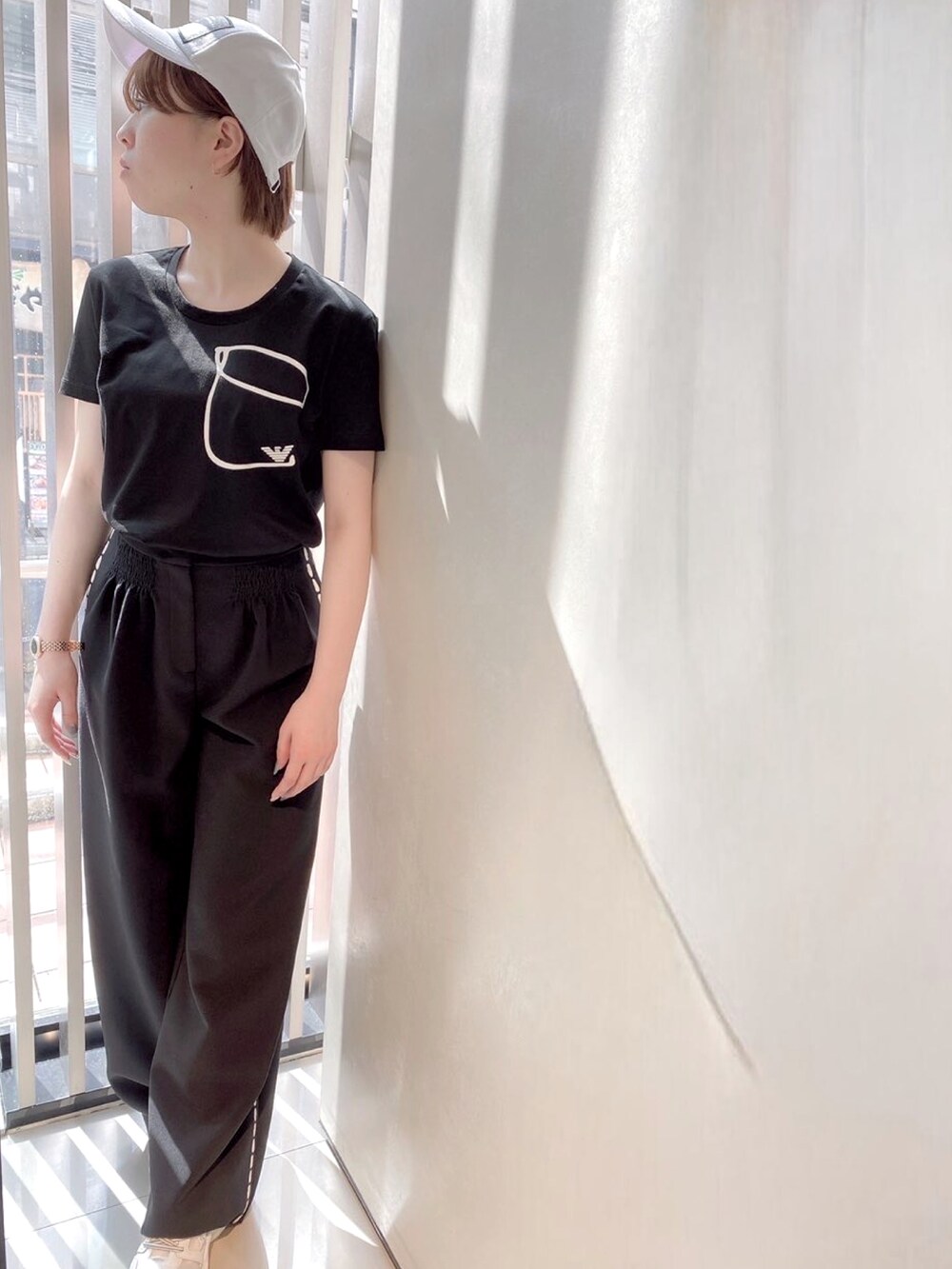 ホワイト系のTシャツ/カットソー、ブラック系のパンツ、ホワイト系のスニーカーを着用したレディースの夏コーディネートの3枚目の写真