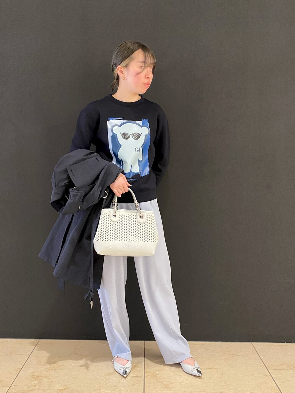 ブルー系のトレンチコート、ブルー系のトップス、ホワイト系のショルダーバッグを着用したレディースの冬コーディネートの2枚目の写真