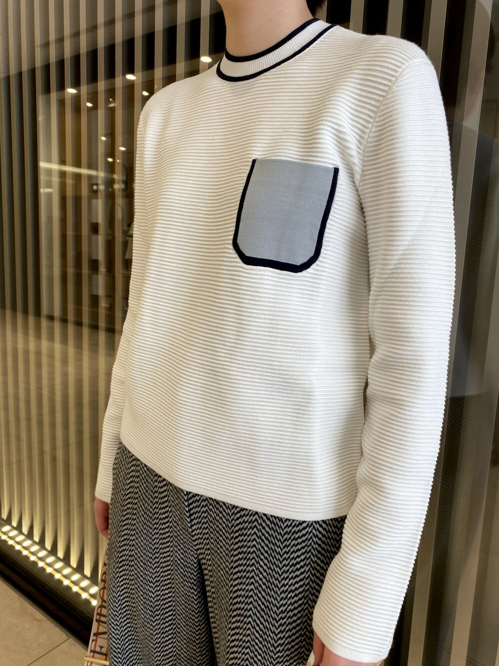 ブラウン系のショルダーバッグ、ブラック系のローファー、ホワイト系のニット/セーターを着用したレディースの夏コーディネートの2枚目の写真