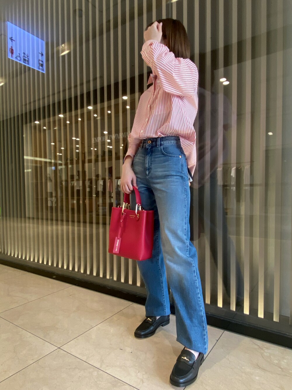 レッド系のシャツ/ブラウス、レッド系のハンドバッグ、ブルー系のデニムパンツを着用したレディースの秋コーディネートの2枚目の写真