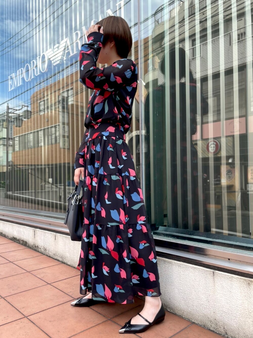 ブラック系のワンピース、ブラック系のハンドバッグ、ブラック系のパンプスを着用したレディースの夏コーディネートの2枚目の写真
