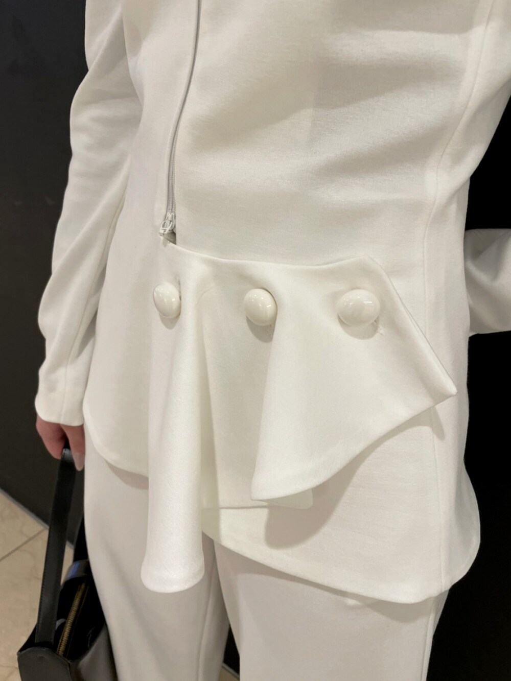 ホワイト系のジャケット/アウター、ホワイト系のパンツ、ブラック系のバッグを着用したレディースの冬コーディネートの2枚目の写真