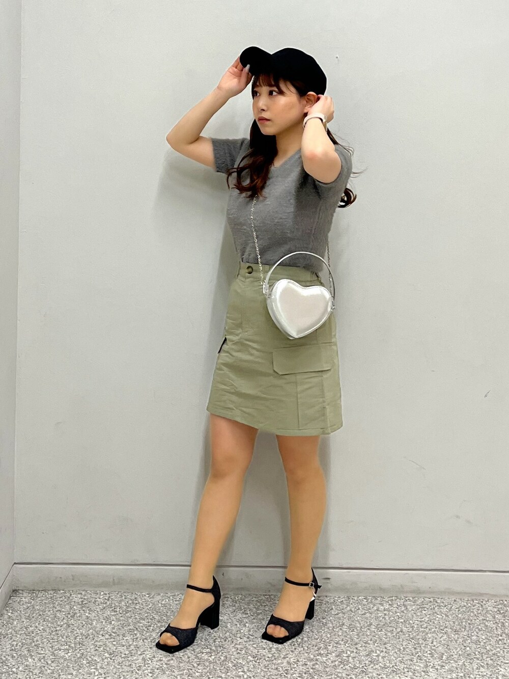 グリーン系のスカート、ベージュ系のニット/セーター、シルバー系のショルダーバッグを着用したレディースの春コーディネートの2枚目の写真