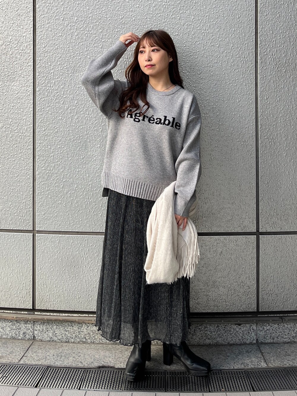 グレー系のニット/セーター、ブラック系のスカート、ホワイト系のマフラーを着用したレディースの秋コーディネートの2枚目の写真