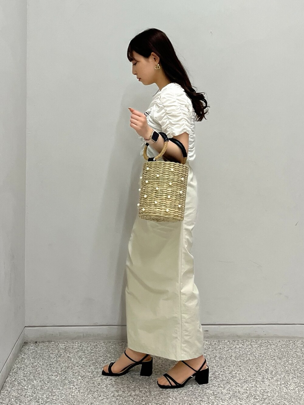 ホワイト系のTシャツ/カットソー、ベージュ系のスカート、ブラック系のかごバッグを着用したレディースの春コーディネートの2枚目の写真