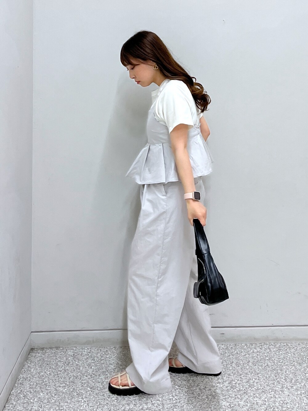 ホワイト系のサンダル、ブラック系のショルダーバッグ、グレー系のベストを着用したレディースの春コーディネートの2枚目の写真