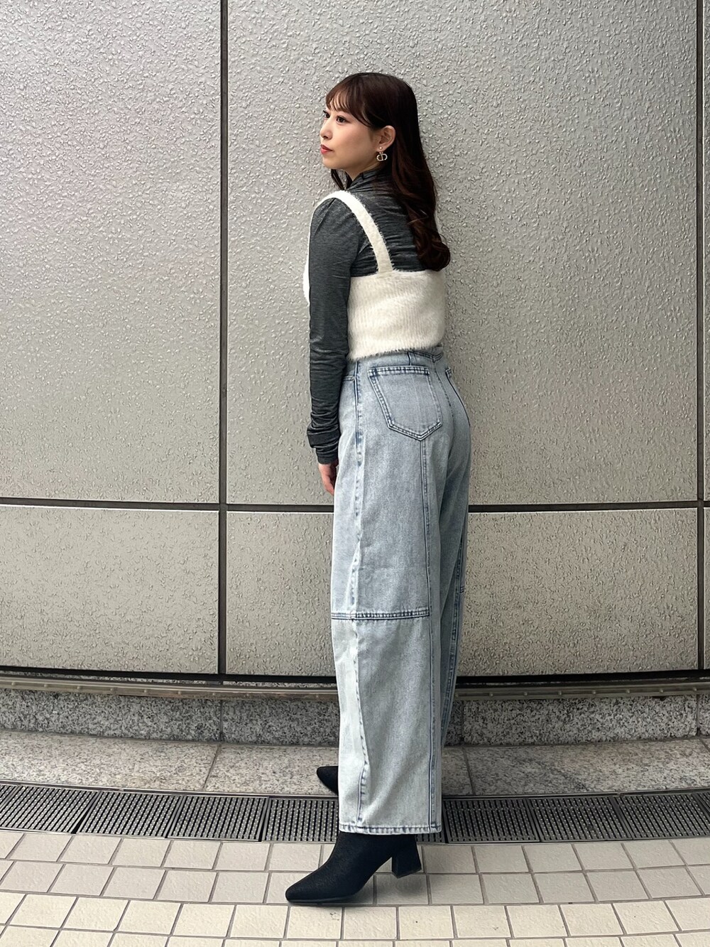 ホワイト系のベスト、ブルー系のデニムパンツを着用したレディースの冬コーディネートの2枚目の写真