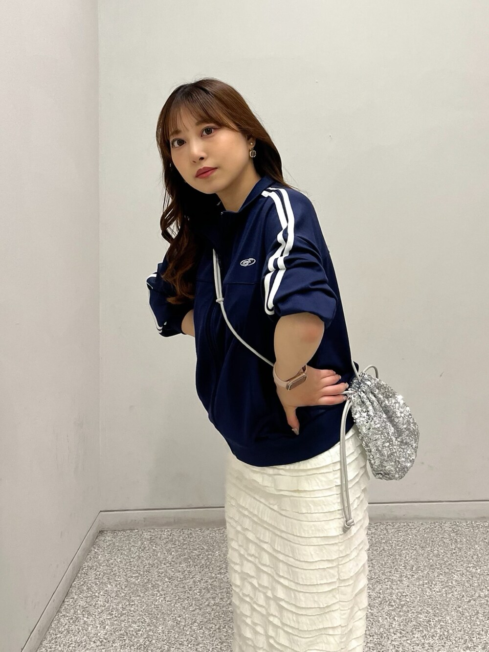 ブルー系のブルゾン、ホワイト系のスカート、シルバー系のハンドバッグを着用したレディースの春コーディネートの3枚目の写真