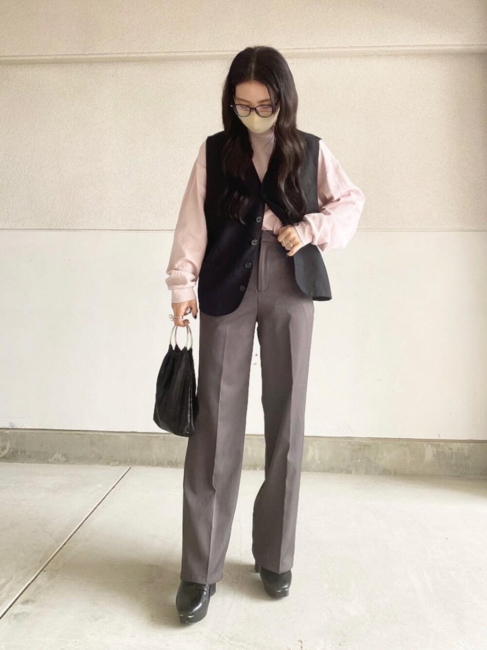 ブラック系のブーツ、ブラック系のハンドバッグ、ブラック系のベストを着用したレディースの春コーディネートの3枚目の写真