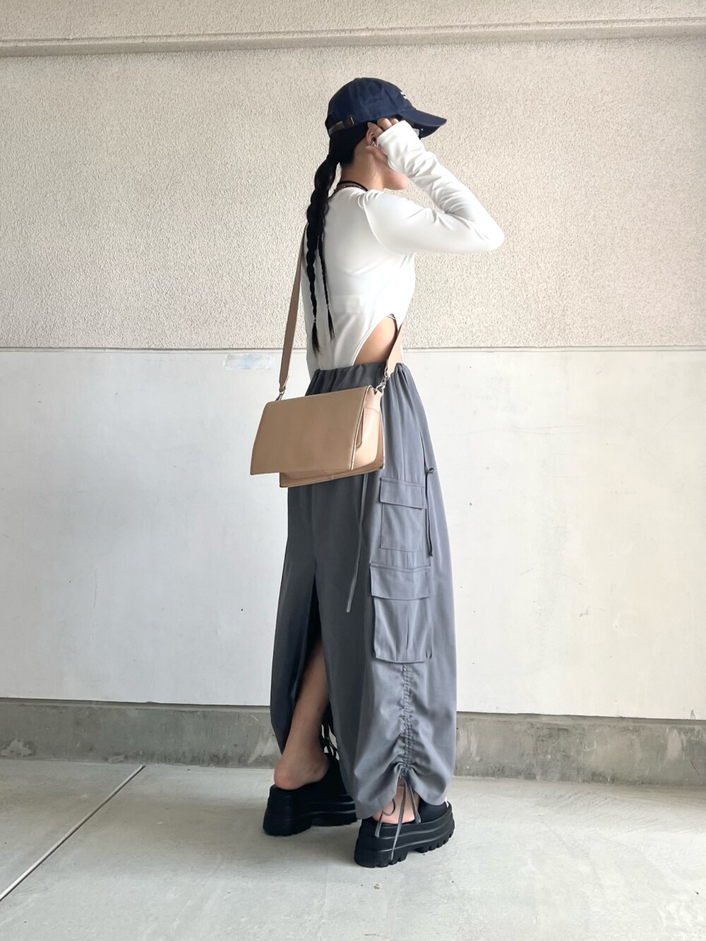 グレー系のスカート、ホワイト系のトップス、ベージュ系のショルダーバッグを着用したレディースの夏コーディネートの5枚目の写真