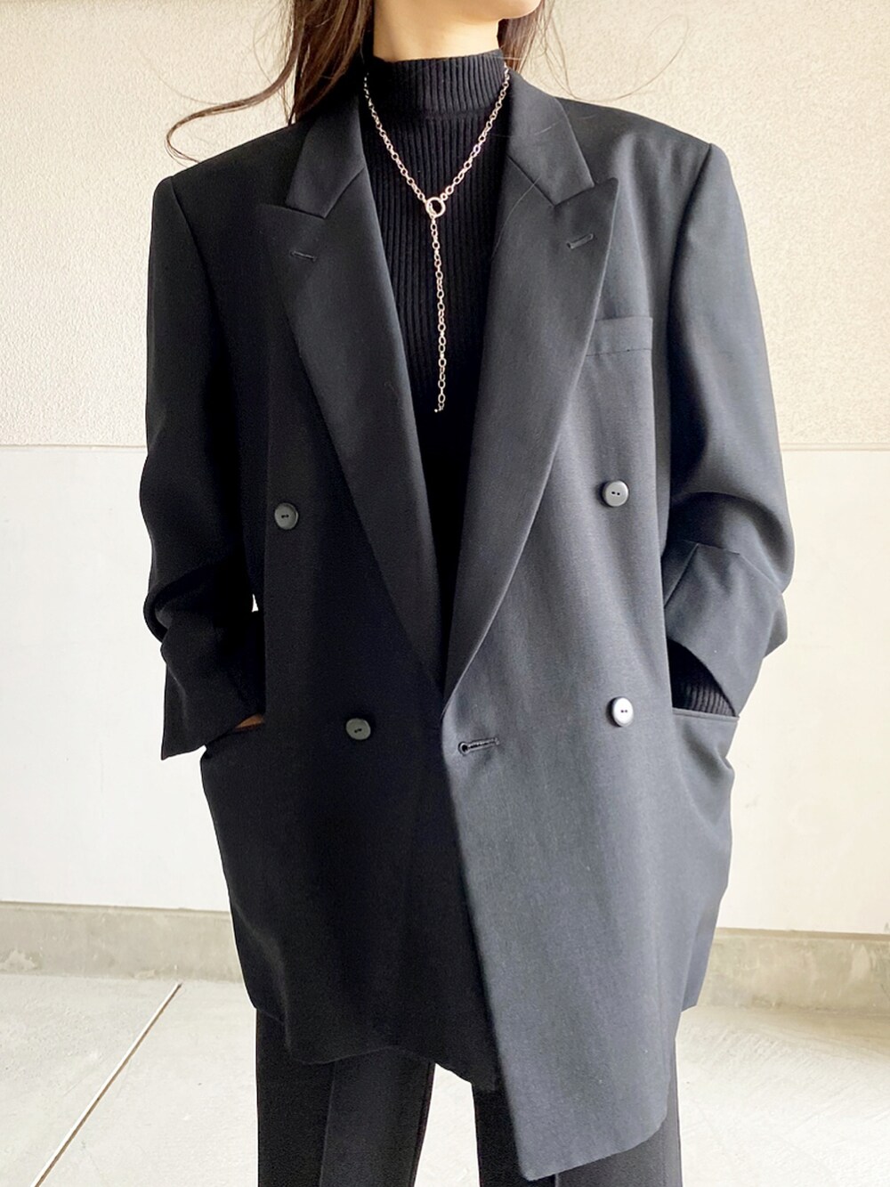 ブラック系のテーラードジャケット、ブラック系のブーツ、ブラック系のパンツを着用したレディースの冬コーディネートの3枚目の写真