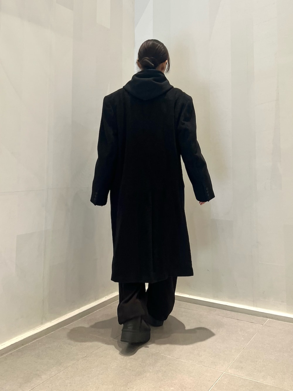 ブラック系のスウェットパンツ、ブラック系のパーカー、ブラック系のチェスターコートを着用したレディースの冬コーディネートの4枚目の写真