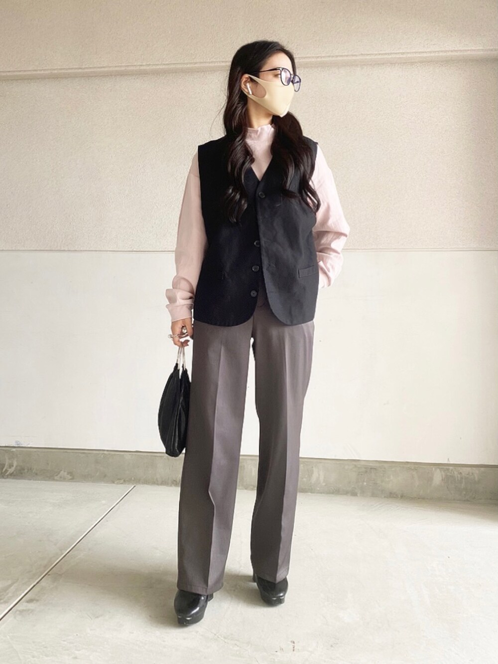 ブラック系のブーツ、ブラック系のハンドバッグ、ブラック系のベストを着用したレディースの春コーディネートの2枚目の写真