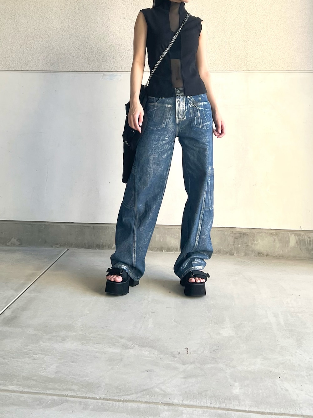 ブラック系のタンクトップ、ブルー系のデニムパンツ、ブラック系のサンダルを着用したレディースの夏コーディネートの3枚目の写真