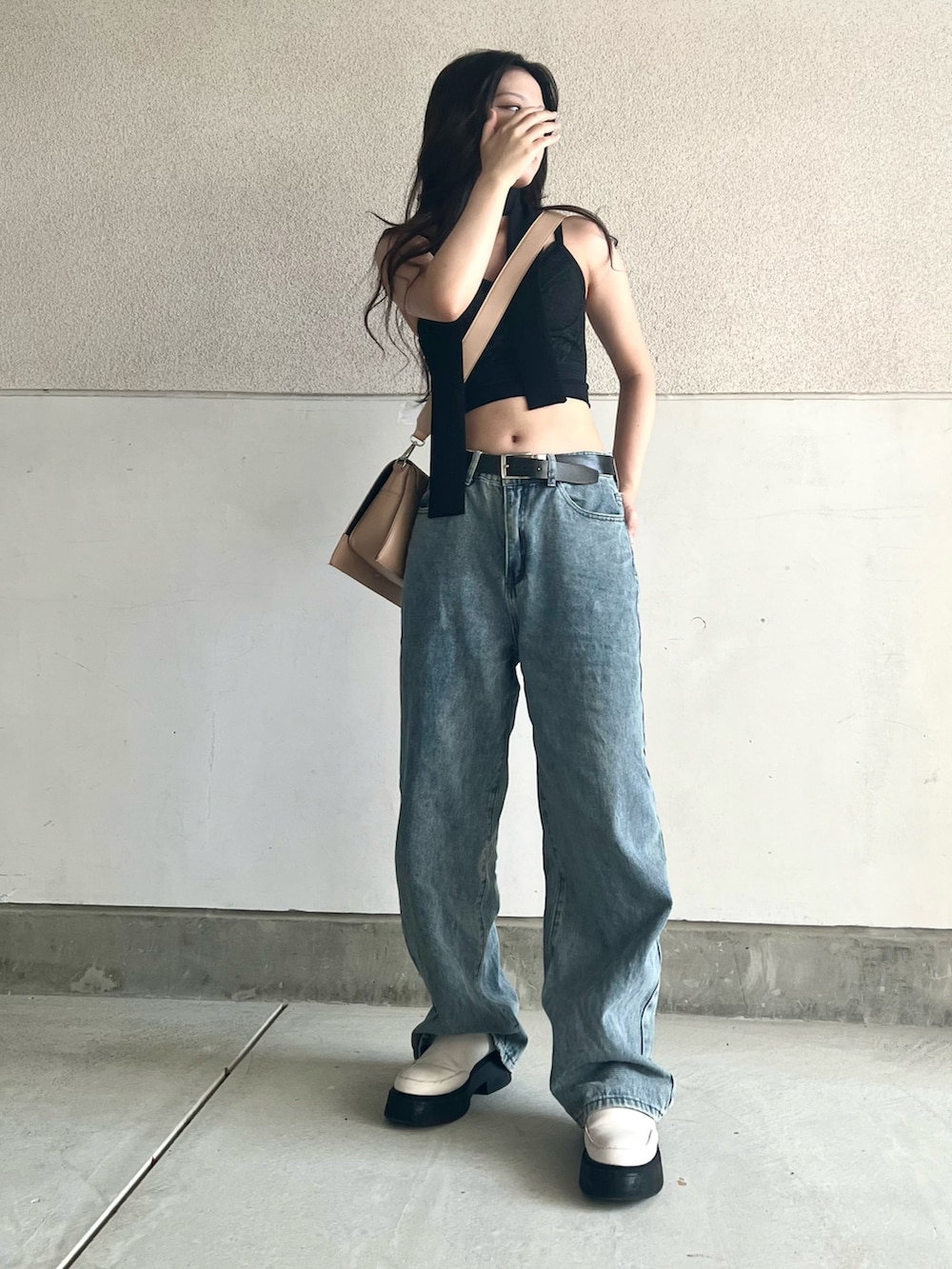 ブルー系のデニムパンツ、ベージュ系のショルダーバッグ、ホワイト系のシューズを着用したレディースの夏コーディネートの3枚目の写真