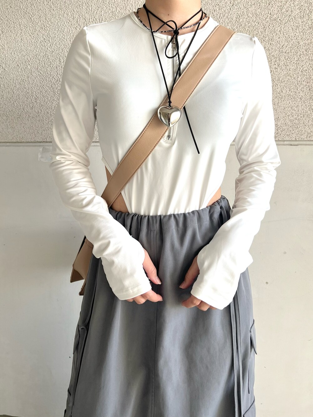 グレー系のスカート、ホワイト系のトップス、ベージュ系のショルダーバッグを着用したレディースの夏コーディネートの2枚目の写真