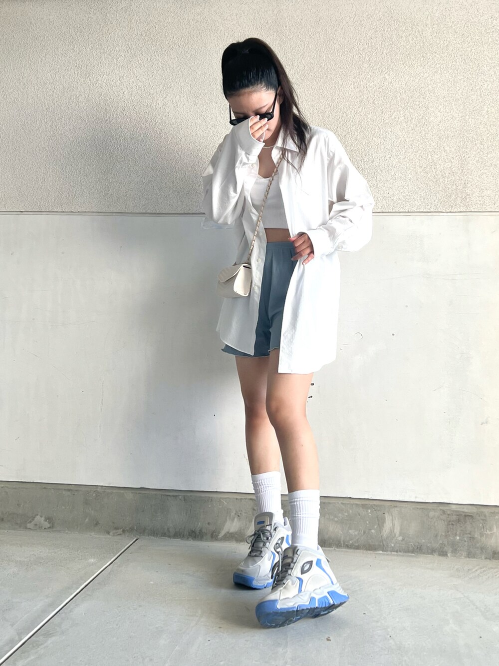 グレー系のスニーカー、ホワイト系のシャツ/ブラウス、ホワイト系のショルダーバッグを着用したレディースの夏コーディネートの5枚目の写真
