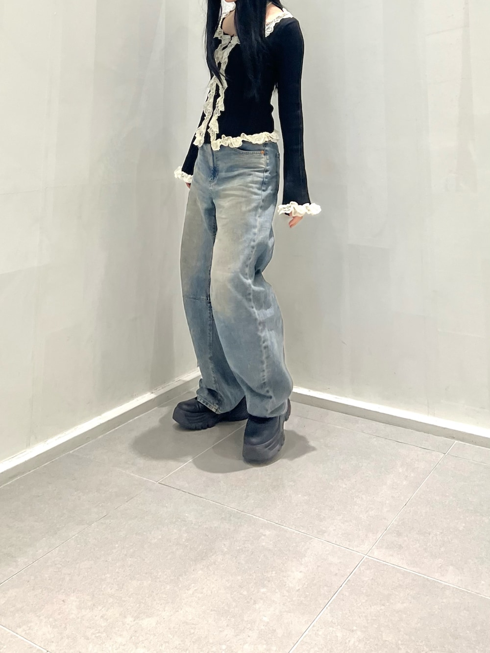 ブラック系のトップス、ブルー系のデニムパンツ、ブラック系のシューズを着用したレディースの秋コーディネートの4枚目の写真