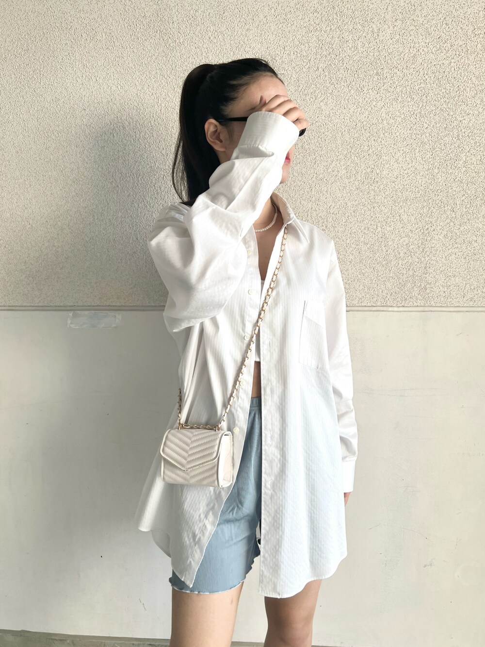 グレー系のスニーカー、ホワイト系のシャツ/ブラウス、ホワイト系のショルダーバッグを着用したレディースの夏コーディネートの3枚目の写真