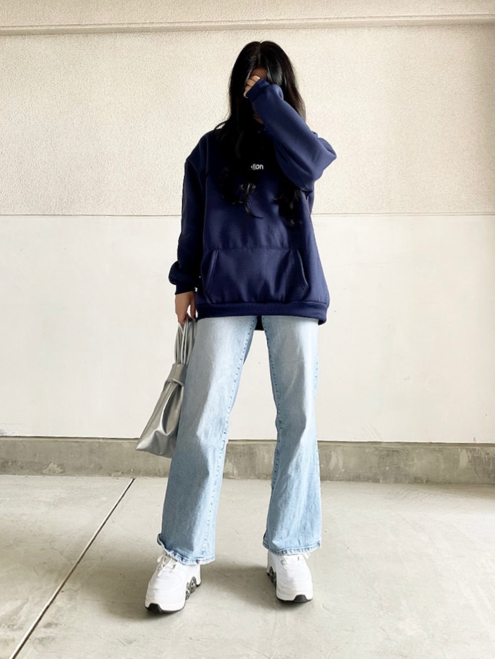 ブルー系のパーカー、ブルー系のデニムパンツ、ホワイト系のスニーカーを着用したレディースの春コーディネートの2枚目の写真