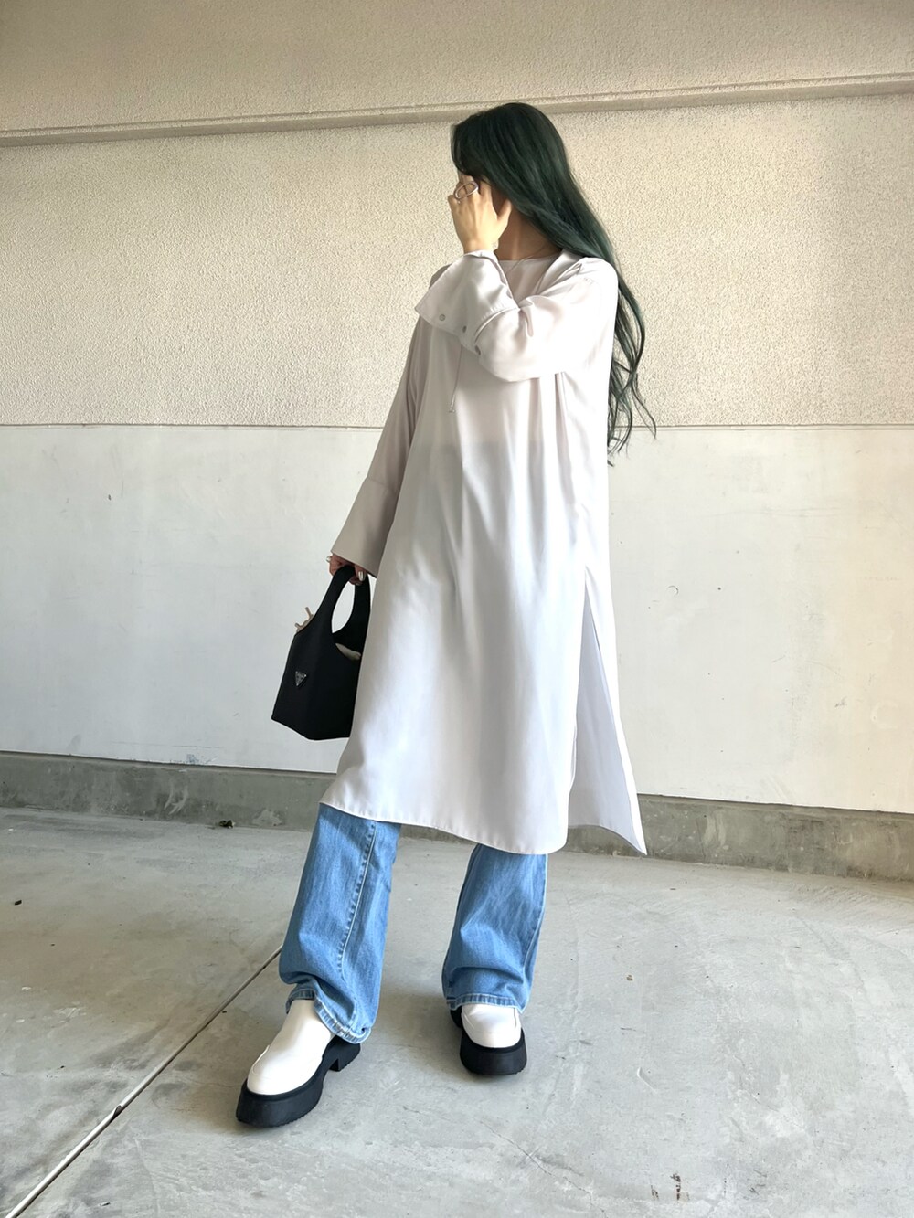 ブルー系のパンツ、ベージュ系のワンピース、ホワイト系のシューズを着用したレディースの秋コーディネートの3枚目の写真
