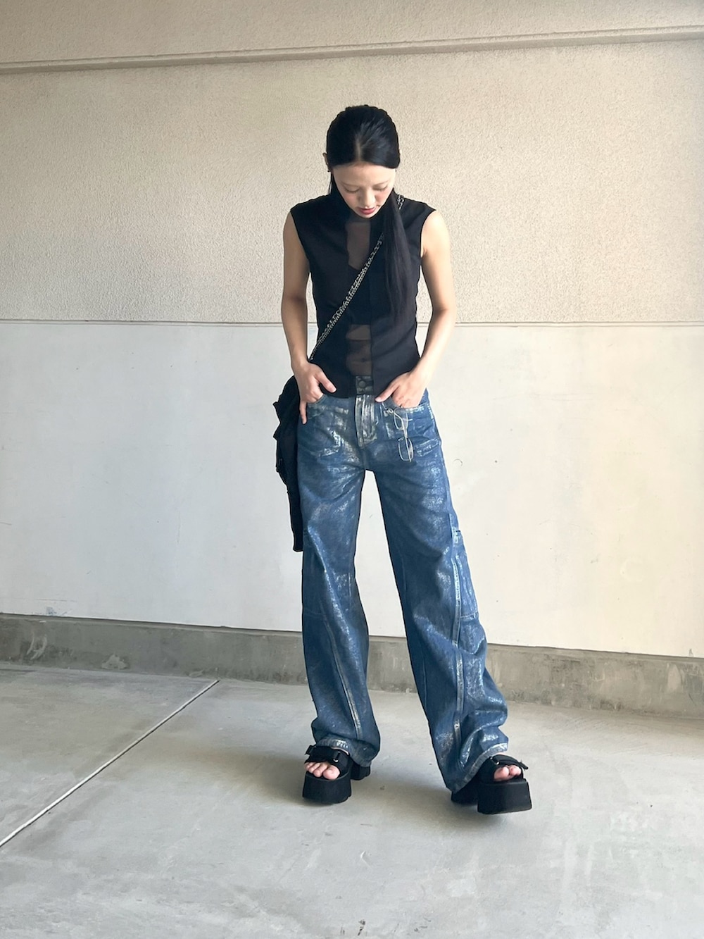 ブラック系のタンクトップ、ブルー系のデニムパンツ、ブラック系のサンダルを着用したレディースの夏コーディネートの5枚目の写真