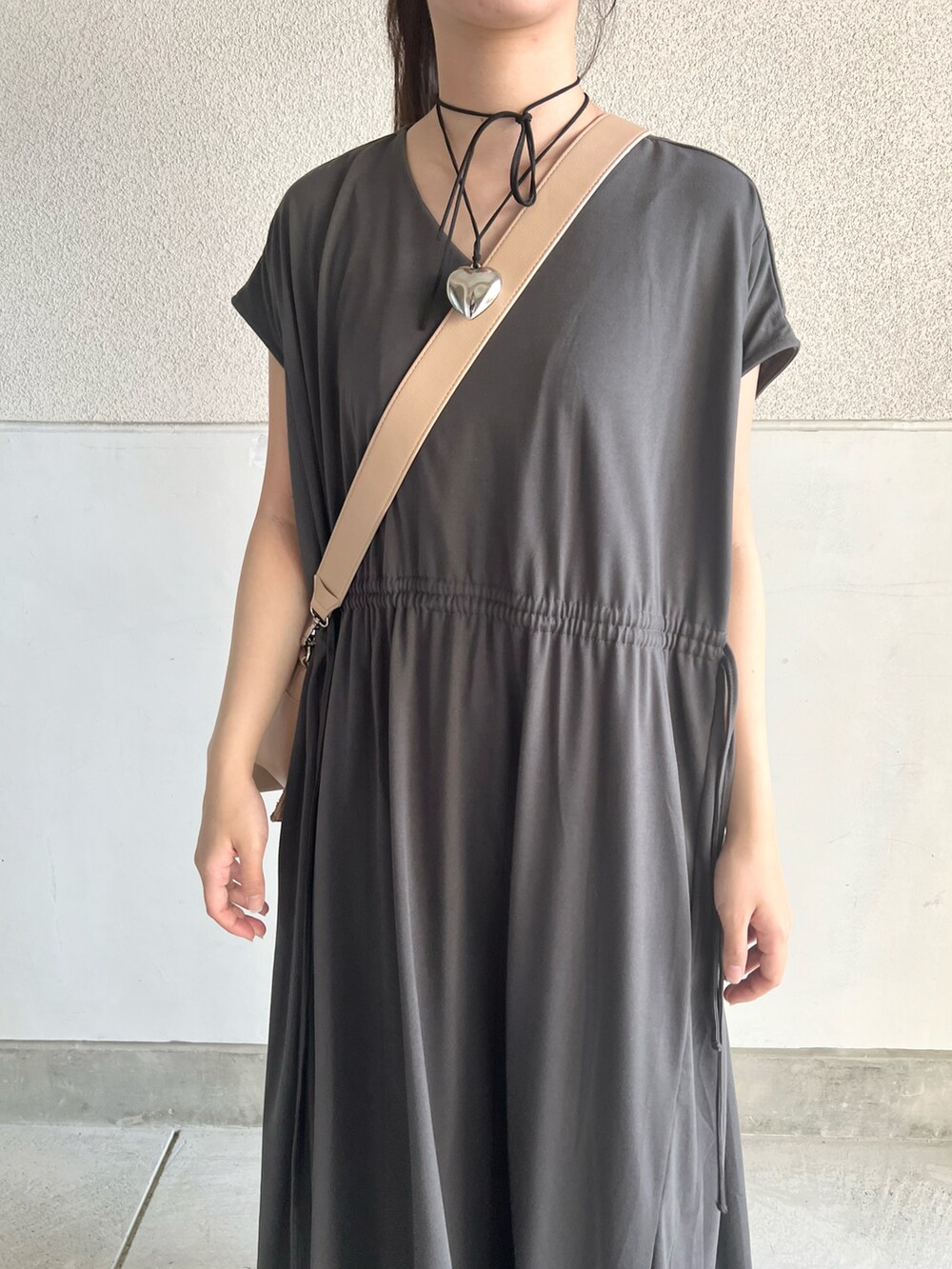 グレー系のワンピース、ベージュ系のショルダーバッグ、ブラック系のシューズを着用したレディースの夏コーディネートの2枚目の写真
