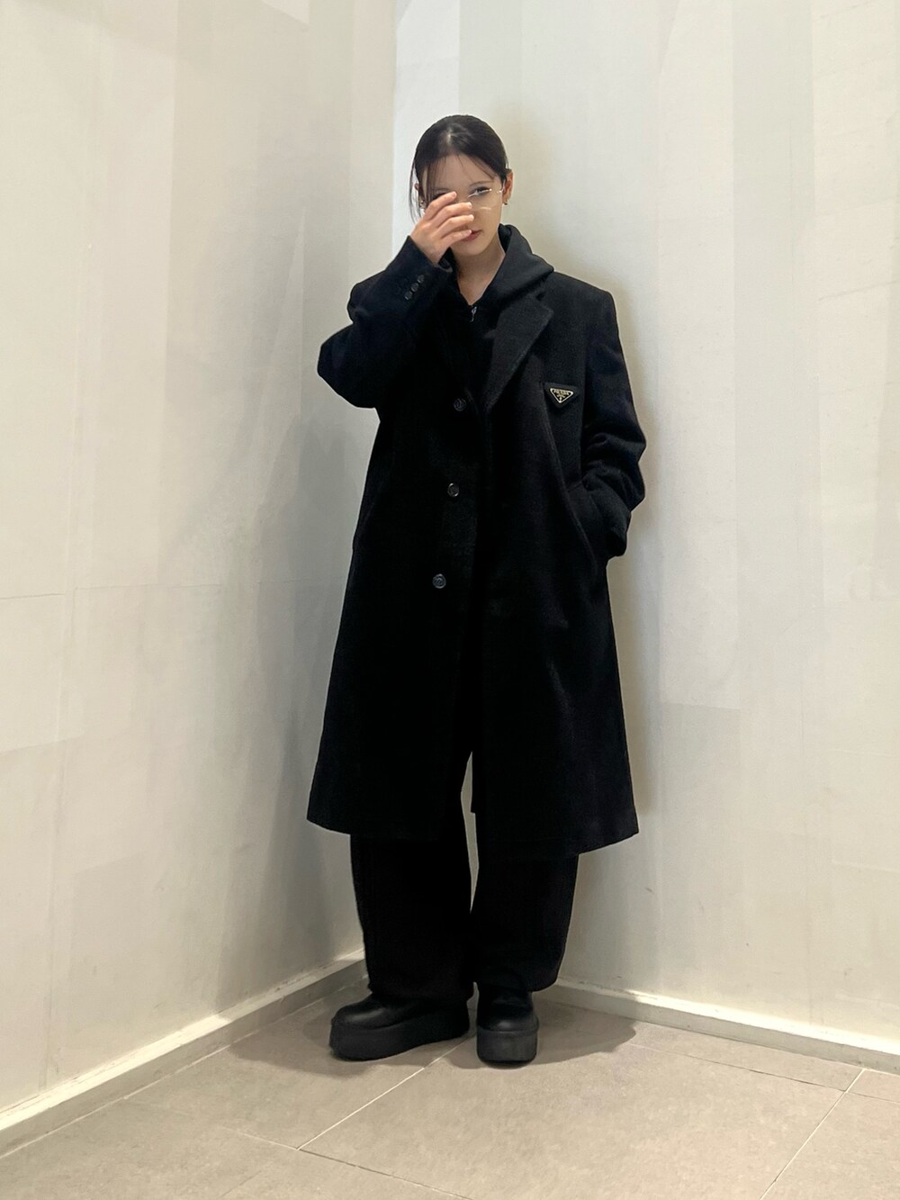 ブラック系のスウェットパンツ、ブラック系のパーカー、ブラック系のチェスターコートを着用したレディースの冬コーディネートの5枚目の写真