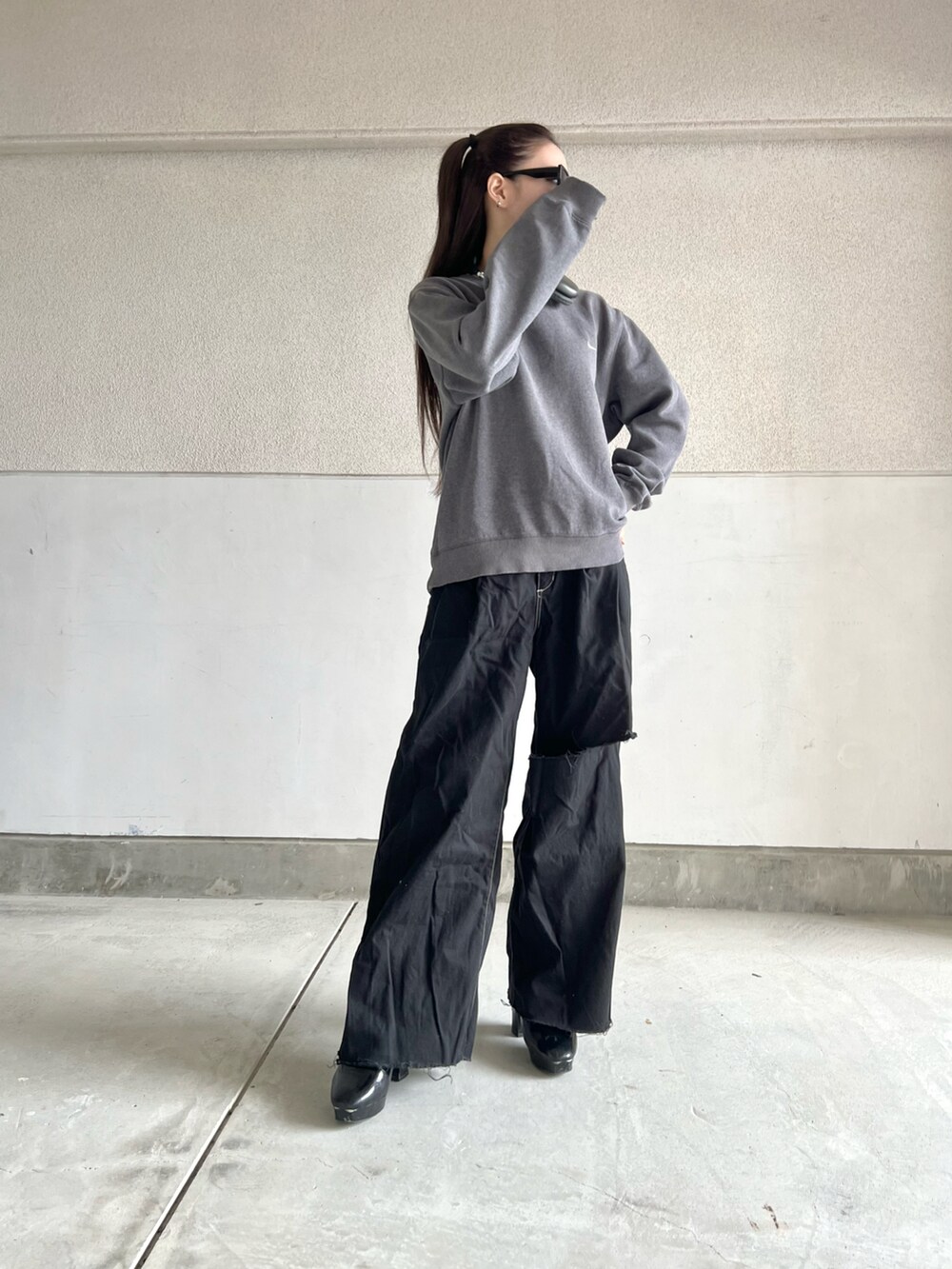 グレー系のスウェット、ブラック系のパンツ、ブラック系のブーツを着用したレディースの秋コーディネートの2枚目の写真