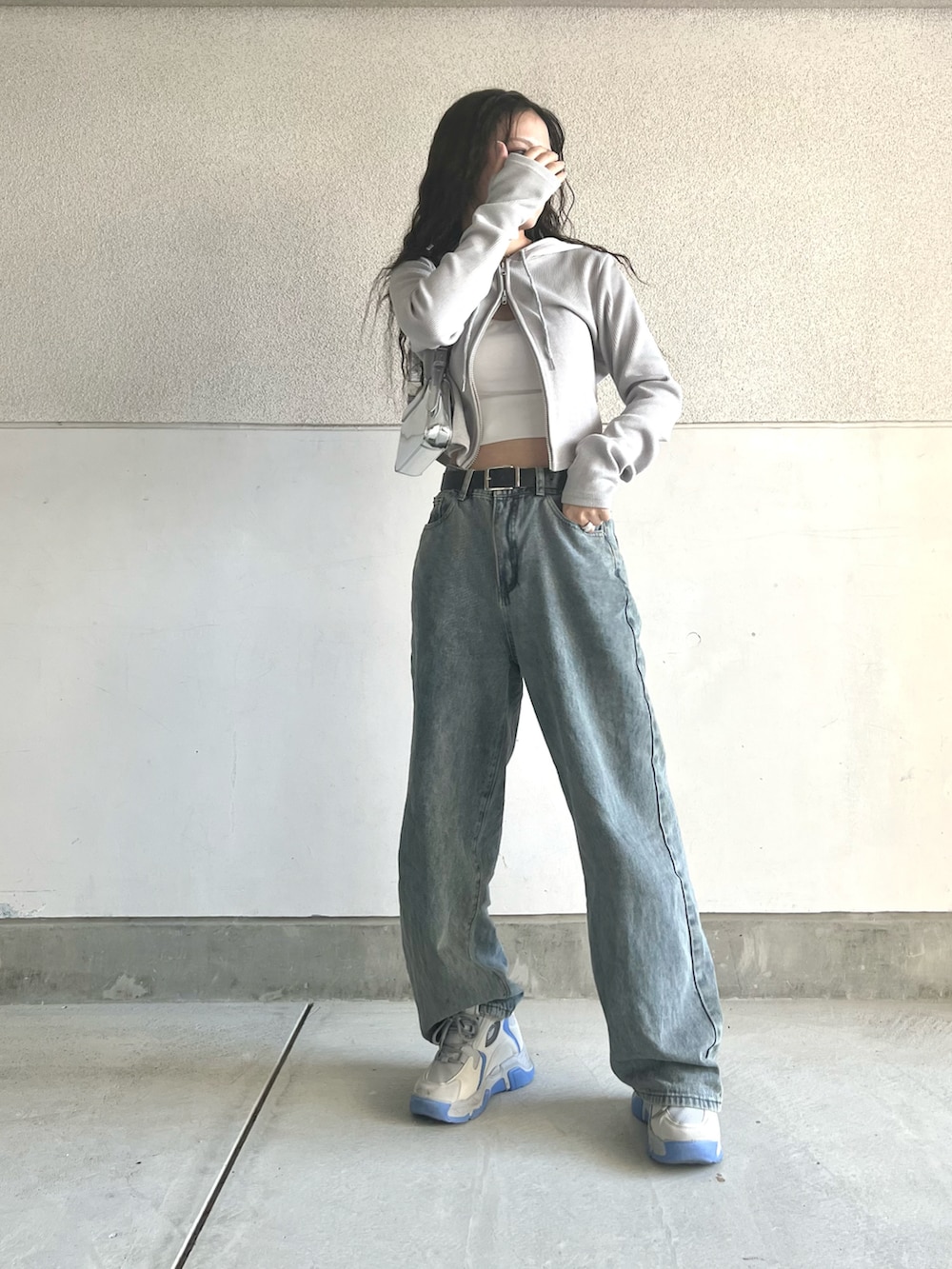グレー系のスニーカー、グレー系のパーカー、ブルー系のデニムパンツを着用したレディースの春コーディネートの3枚目の写真