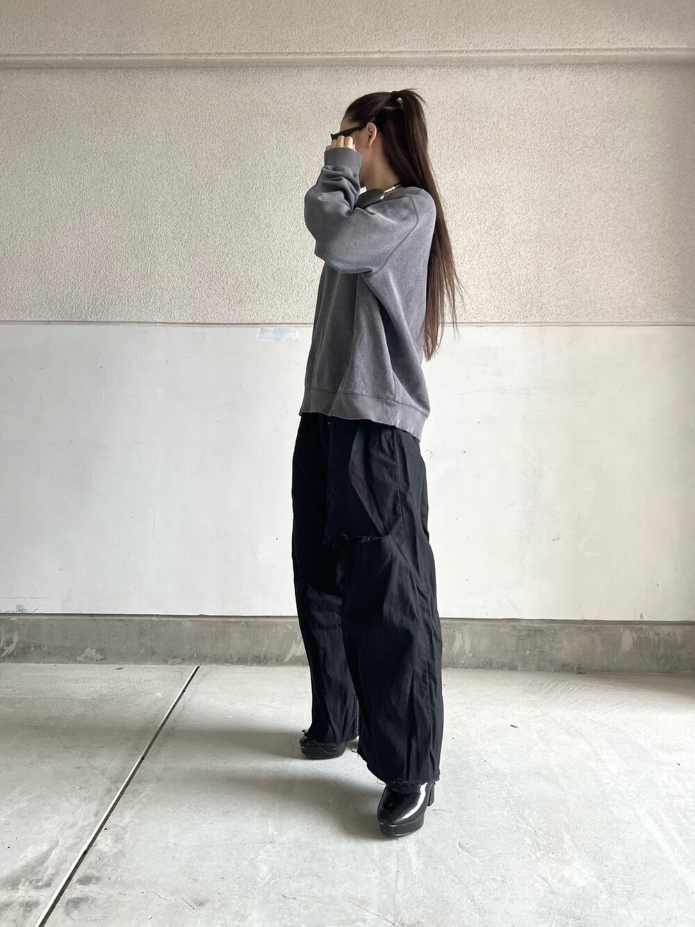 グレー系のスウェット、ブラック系のパンツ、ブラック系のブーツを着用したレディースの秋コーディネートの3枚目の写真