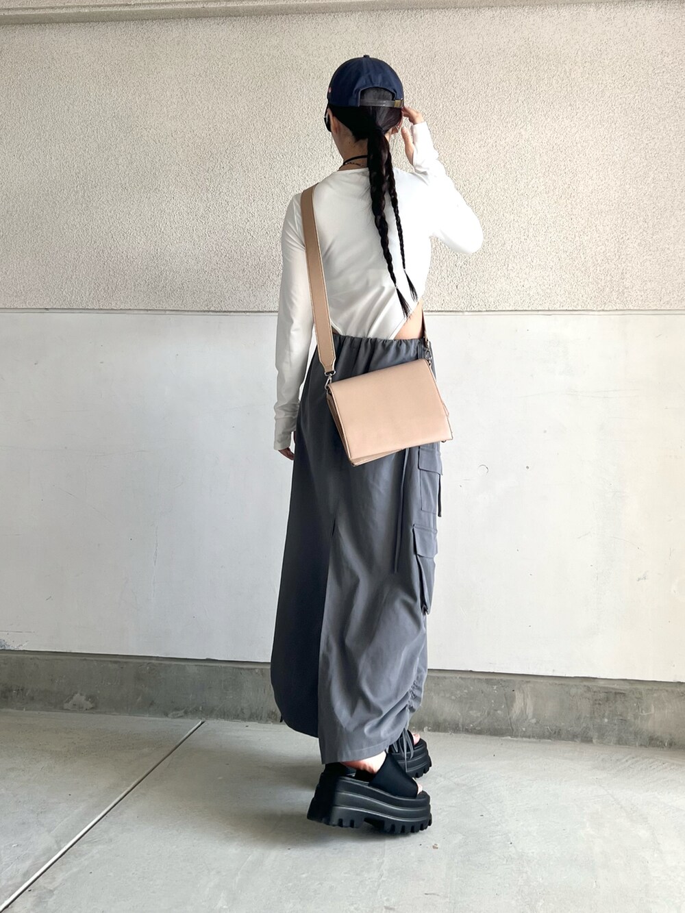 グレー系のスカート、ホワイト系のトップス、ベージュ系のショルダーバッグを着用したレディースの夏コーディネートの3枚目の写真