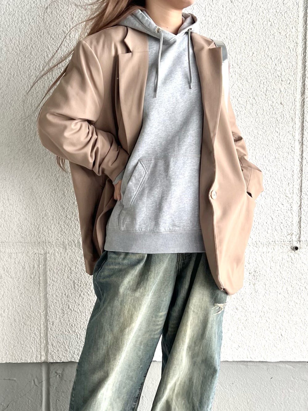 ブラウン系のテーラードジャケット、グレー系のパーカー、ブラック系のブーツを着用したレディースの冬コーディネートの2枚目の写真